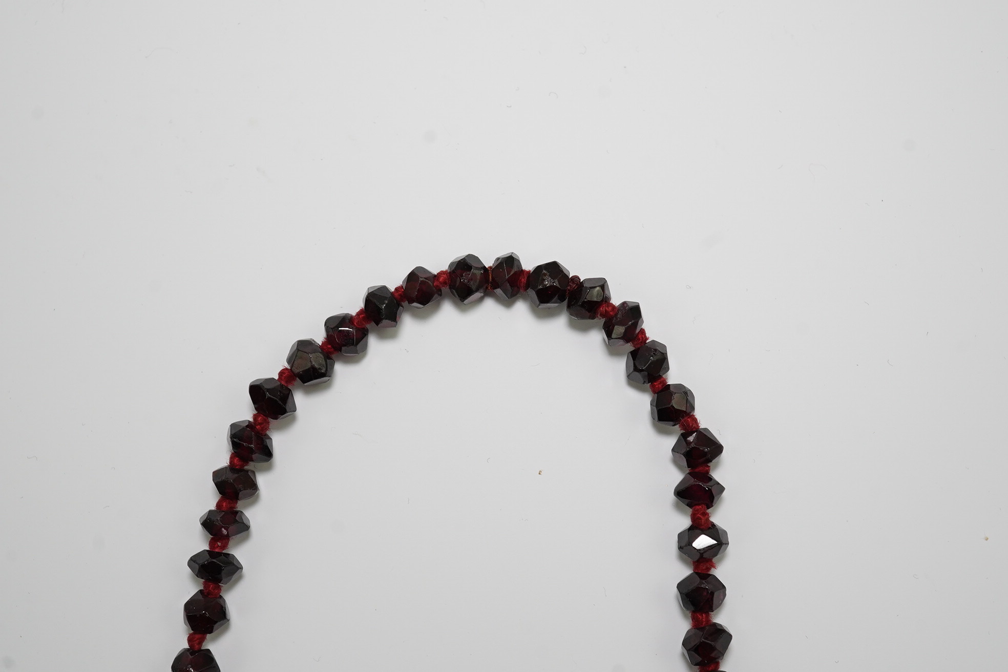 A Victorian facet cut garnet necklace, with cabochon garnet cluster set gold clasp